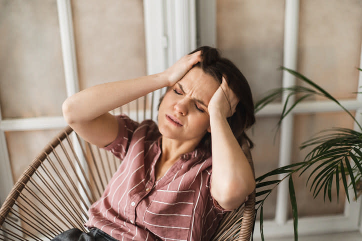 A woman looking distressed and holding her head in her hands