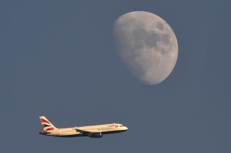 A British Airways passenger plane flies in the sky with the moon seen in the background, in London, Britain, January 19, 2016. REUTERS/Toby Melville