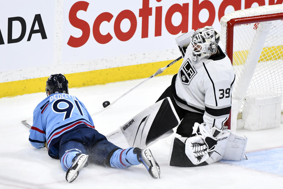 Los Angeles Kings goaltender Cam Talbot (39) directs the puck behind the net as Winnipeg Jets' Cole Perfetti (91) slides past him during the third period of an NHL hockey game in Winnipeg, Manitoba, on Monday, April 1, 2024. (Fred Greenslade/The Canadian Press via AP)