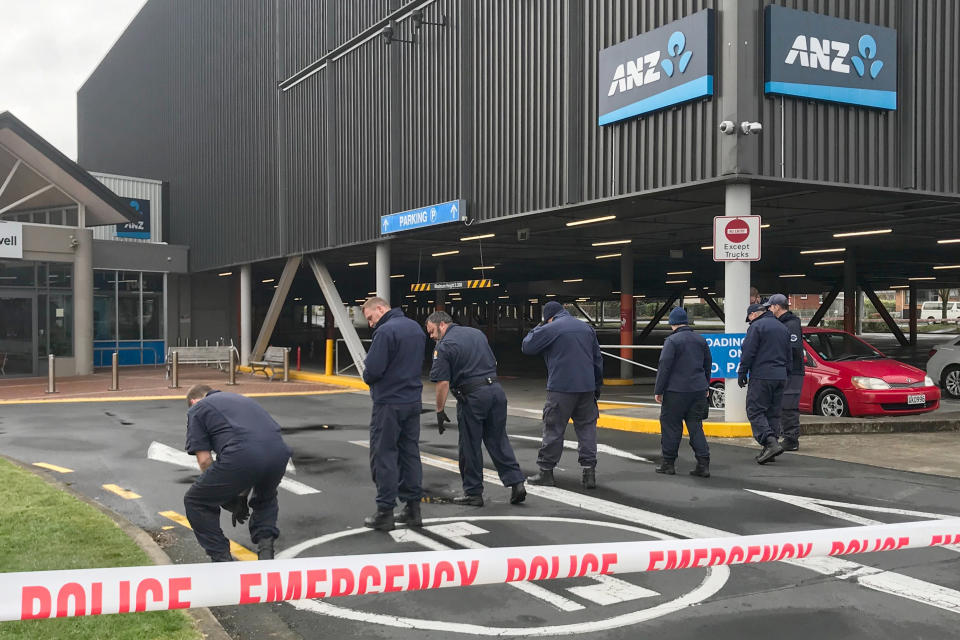 Police search outside the Chartwell Shopping Centre in Hamilton, New Zealand, Thursday, Aug. 6, 2020. Would-be thieves appear to have denoted two homemade bombs at an ATM machine outside a shopping mall early Thursday and left other unexploded bombs behind, according to police. (Belinda Feek/NZ Herald via AP)