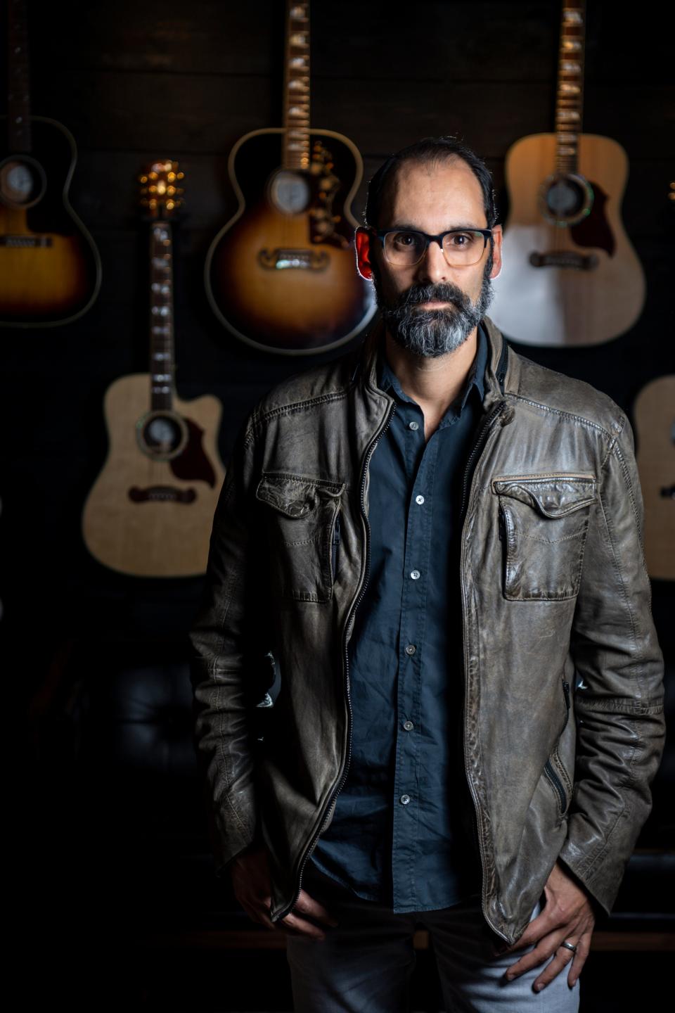 Cesar Gueikian, Gibson Brand President, stands in front of an assortment of acoustic guitars in the backstage lounge at the new Gibson Garage on Tuesday, May 25, 2021, in Nashville, Tenn.