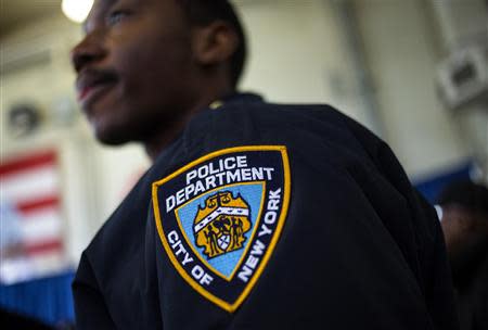 A New York Police Department officer is seen as Mayor Bill de Blasio attends a news conference in the Brownsville neighborhood in the borough of Brooklyn, New York January 30, 2014. REUTERS/Eric Thayer