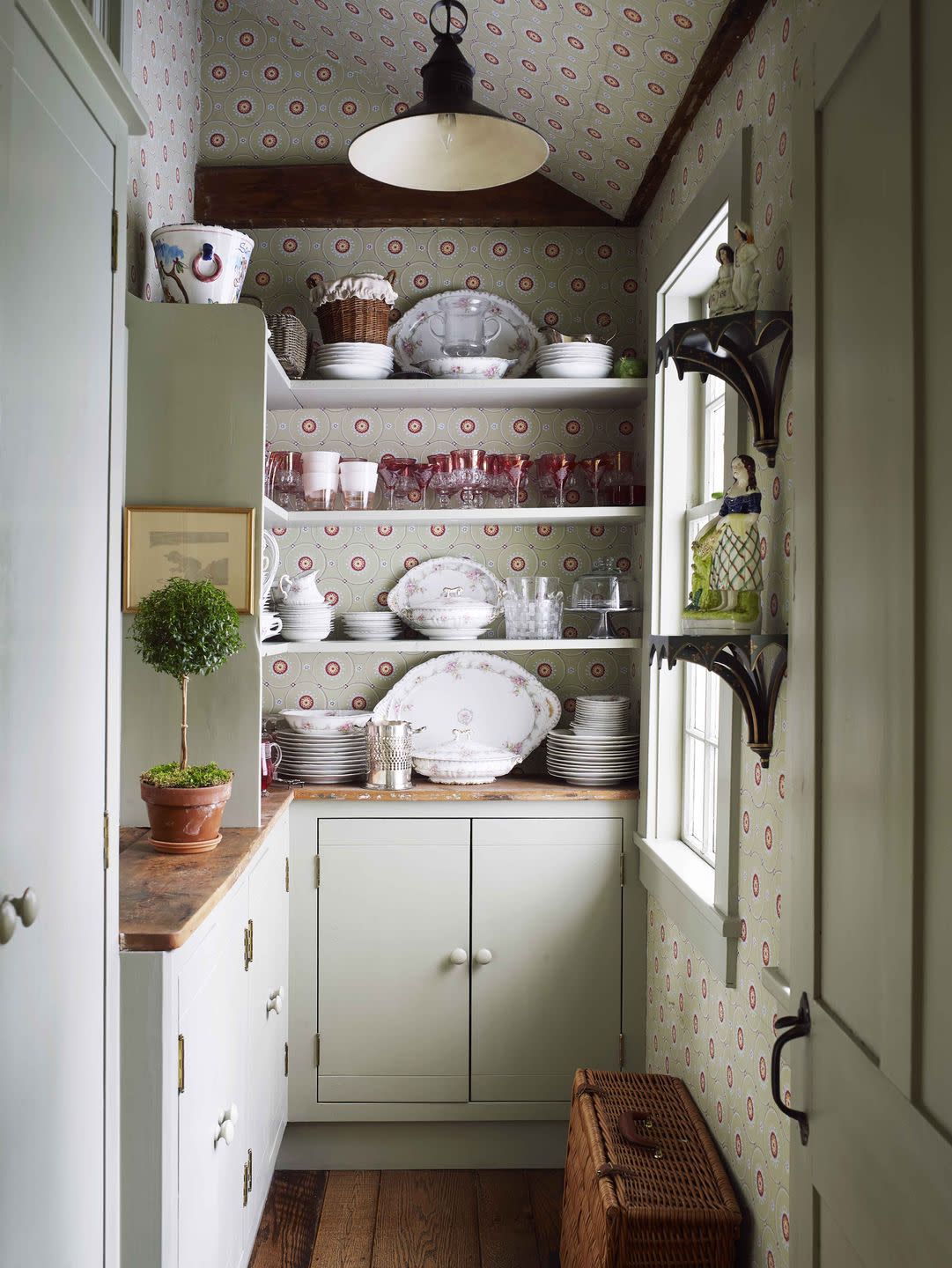 a butler’s pantry walls are covered in a recolored historic parisian pattern open shelves are filled with glasses and dishware