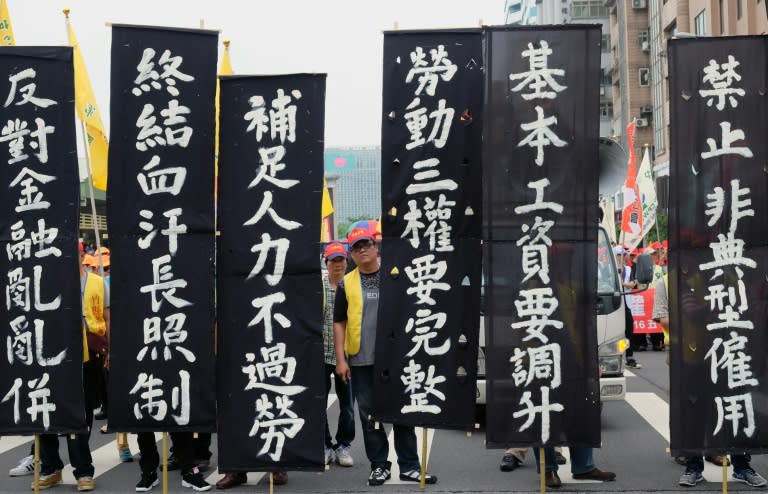 In Taiwan marchers display signs reading "raise the basic labor's salary" in Taipei on May 1, 2016 as part of annual May Day protests