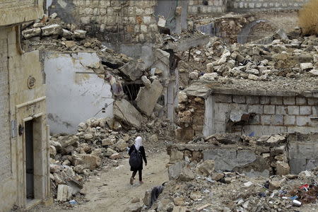 A school girl walks past damaged buildings in the rebel-controlled area of Maaret al-Numan town in Idlib province, Syria October 28, 2015. REUTERS/Khalil Ashawi