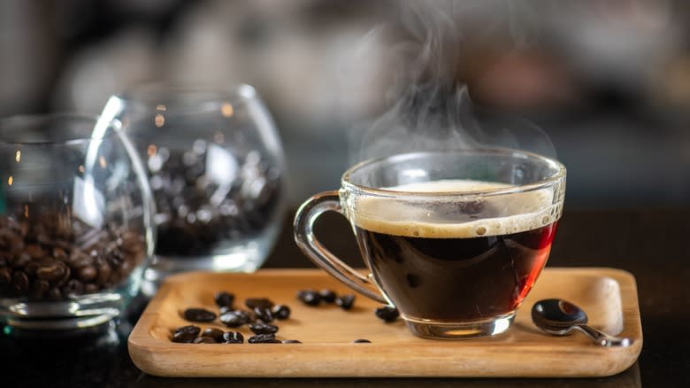 steaming cup of coffee with coffee bean nearby