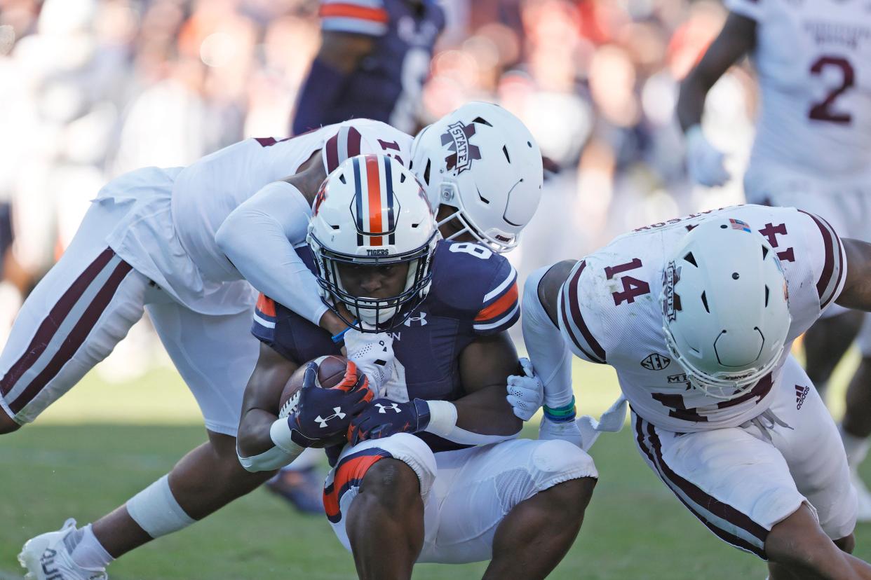 Auburn running back Shaun Shivers (8) is tackled by Mississippi State safety Collin Duncan (19) and linebacker Nathaniel Watson (14) on Nov. 13, 2021, in Auburn, Alabama.