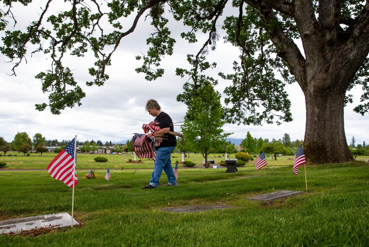 Longtime Lane Memorial Gardens funeral director Dee Harbison in 2021 leads a crew of volunteers in placing United States flags on the graves of service members in honor of Memorial Day.