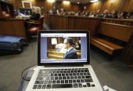 Oscar Pistorius is viewed on a laptop as he sits in the dock in court in Pretoria, South Africa, Friday, March 14, 2014 on the tenth day of proceedings. Pistorius is charged with the shooting death of his girlfriend Reeva Steenkamp on Valentines Day in 2013. (AP Photo/Kim Ludbrook, Pool)