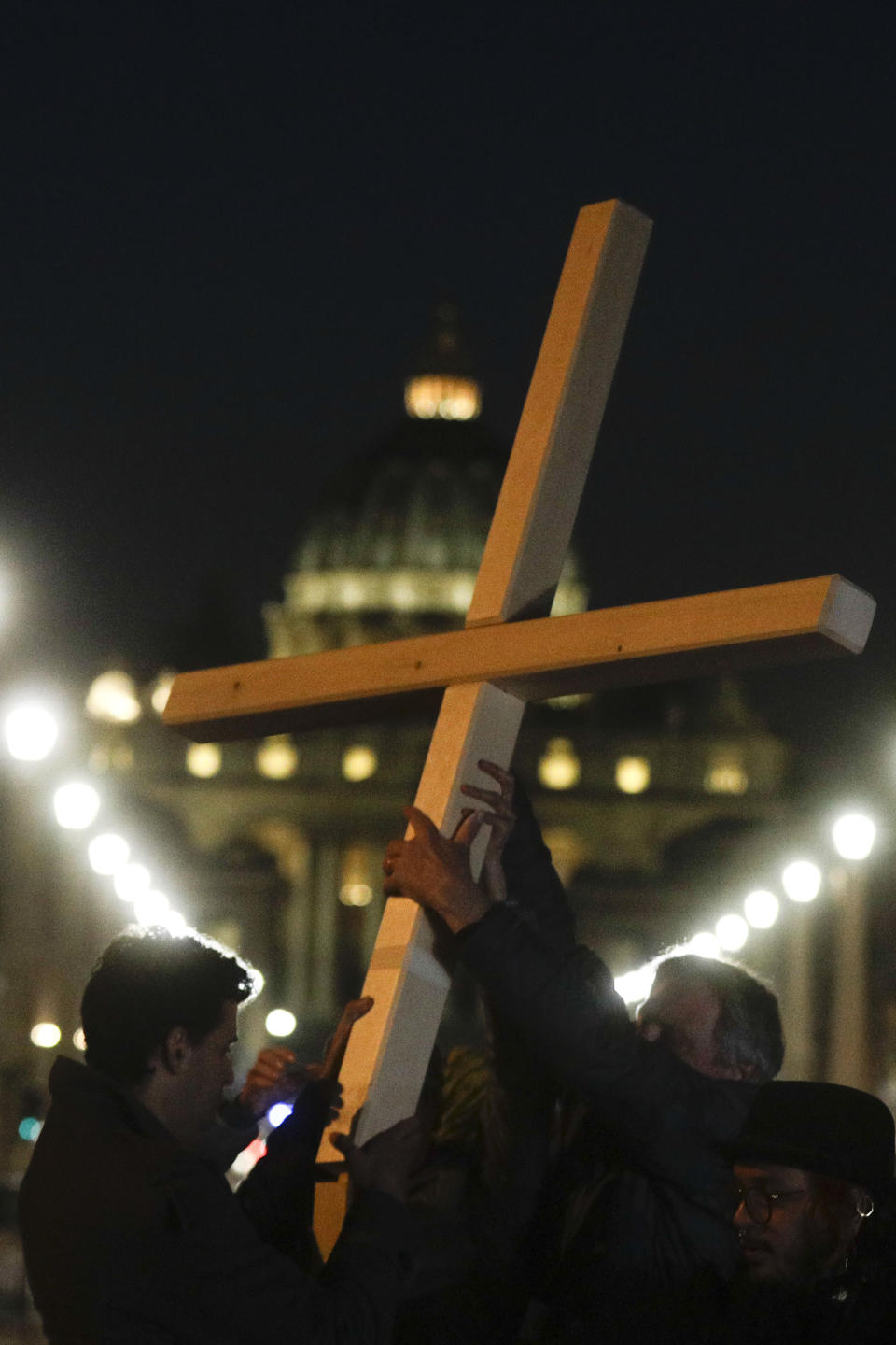 FILE - Survivors of sex abuse hold a cross as they gather in front of Via della Conciliazione, the road leading to St. Peter's Square, visible in background, during a twilight vigil prayer of the victims of sex abuse, in Rome, Thursday, Feb. 21, 2019. Five years ago this week, Francis convened an unprecedented summit of bishops from around the world to impress on them that clergy abuse was a global problem and they needed to address it, but now, five years later, despite new church laws to hold bishops accountable and promises to do better, the Catholic Church's in-house legal system and pastoral response to victims has proven again to be incapable of dealing with the problem. (AP Photo/Gregorio Borgia, file)