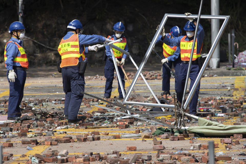 Workers start to clean up the road outside the Hong Kong Polytechnic University in Hong Kong on Wednesday, Nov. 20, 2019. Hong Kong schools have reopened after a six-day shutdown but students were facing transit disruptions as the last protesters remained holed up on a university campus. (AP Photo/Ng Han Guan)