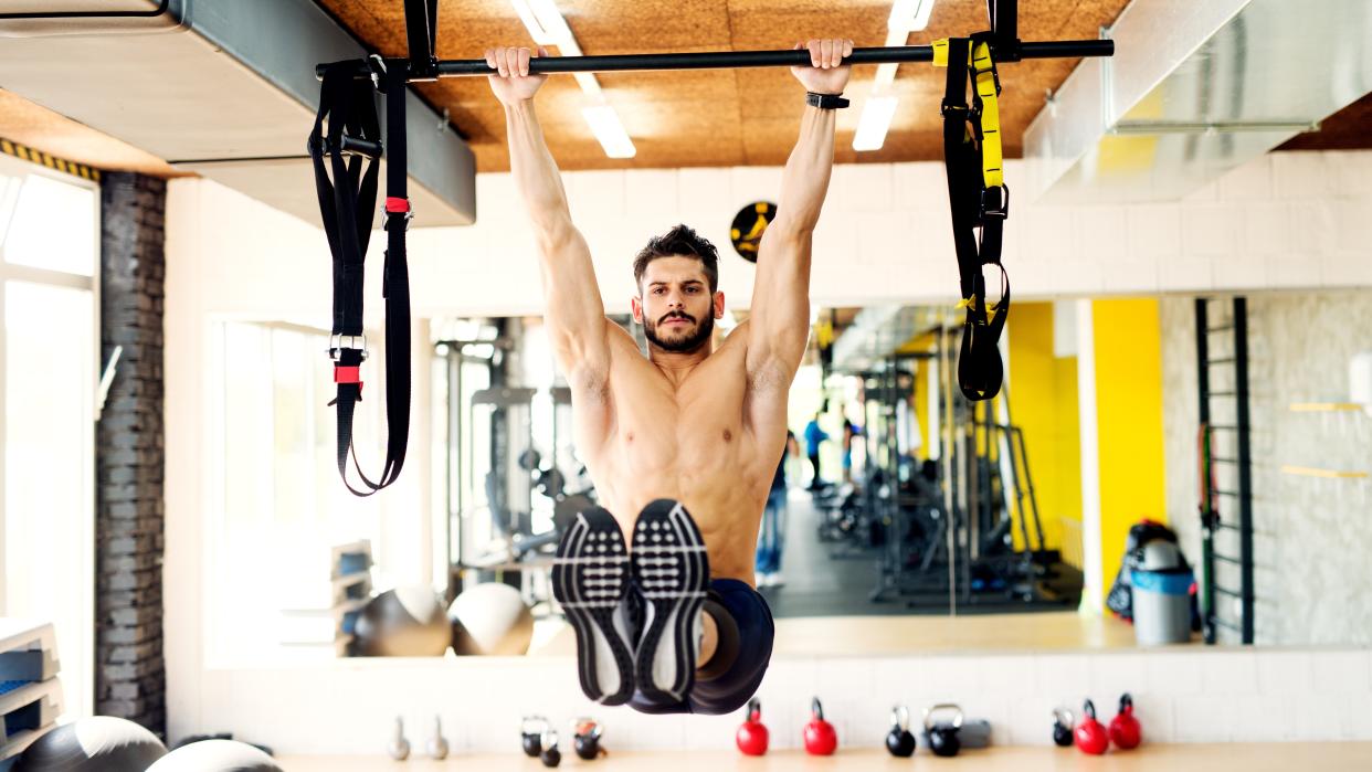   a photo of a man doing hanging leg raises. 