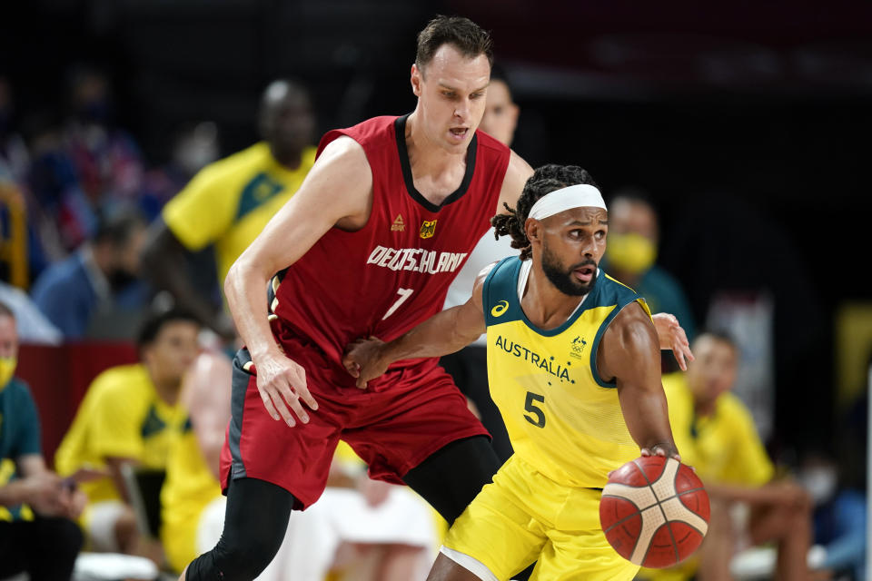 Australia's Patty Mills (5) drives around Germany's Johannes Voigtmann (7) during a men's basketball preliminary round game at the 2020 Summer Olympics, Saturday, July 31, 2021, in Saitama, Japan. (AP Photo/Charlie Neibergall)