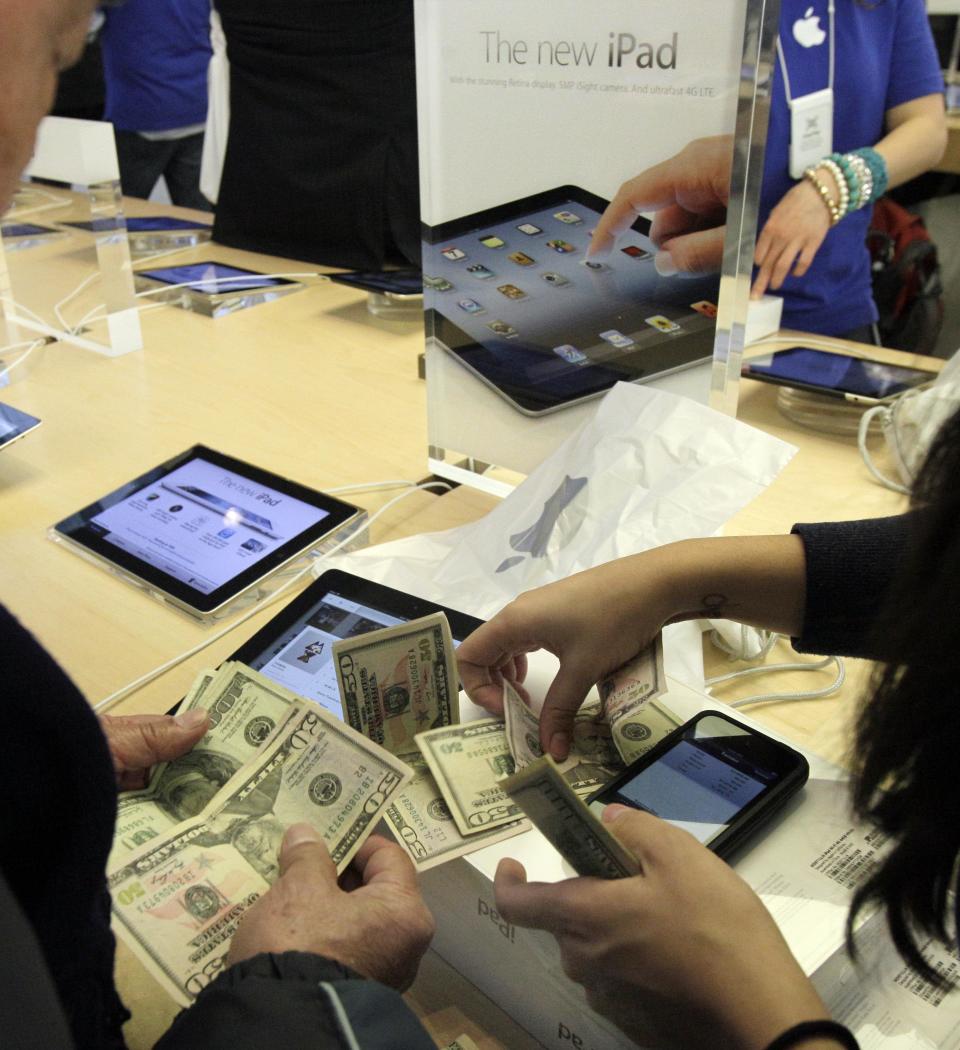 People purchase the new iPad at Apple's flagshop store, in New York, Friday, March 16, 2012. Apple's latest iPad drew die-hard fans to stores in the U.S. and nine other countries Friday, many of whom lined up for hours to be among the first to buy one. (AP Photo/Richard Drew)