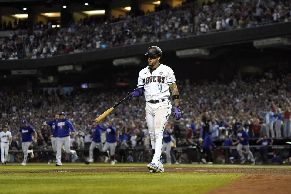 Arizona Diamondbacks' Ketel Marte (4) walks toward the dugout as the Texas Rangers celebrate after winning Game 5 of the baseball World Series against the Arizona Diamondbacks Wednesday, Nov. 1, 2023, in Phoenix. The Rangers won 5-0 to win the series 4-1. (AP Photo/Brynn Anderson)