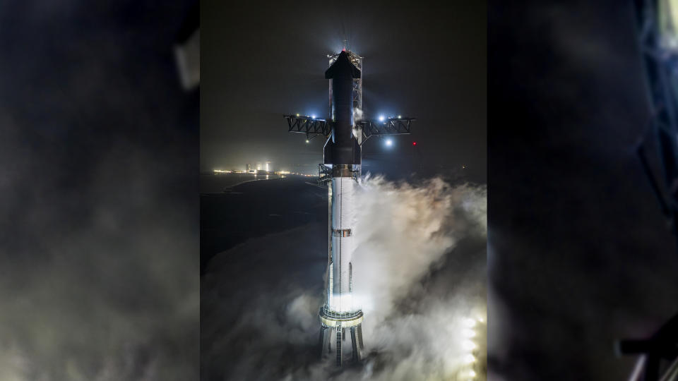 A Starship Flight 3 rocket and Super Heavy booster atop the launch pad at night in a fueling test