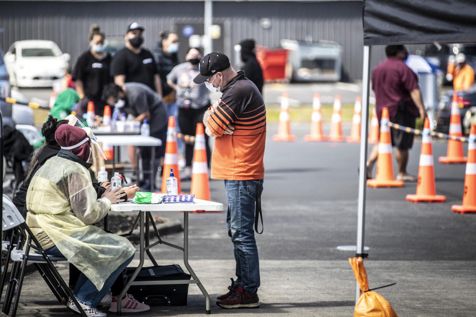 People visit a pop-up vaccination site, Tuesday, Oct. 19, 2021, in suburban Auckland, New Zealand. New Zealand reported its highest number of new coronavirus cases since the pandemic began Tuesday as an outbreak in the largest city of Auckland continued to spread. (Michael Craig/New Zealand Herald via AP)