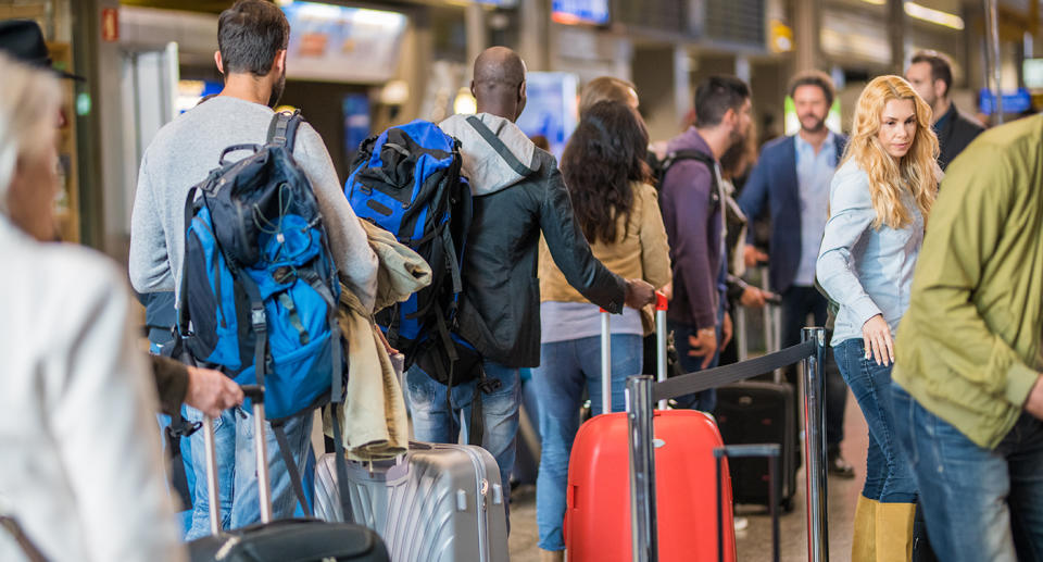 Business people standing with luggage in queue at airport arrival area.