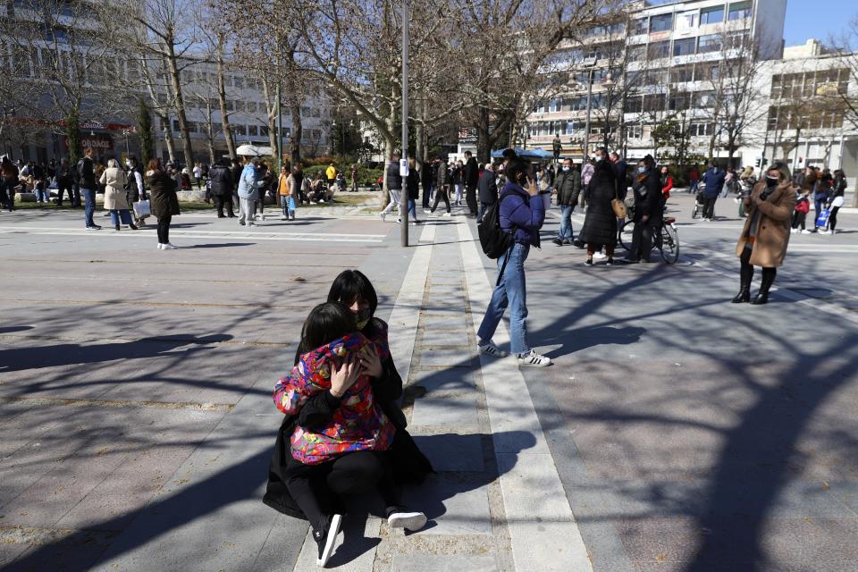 A woman hugs a girl as people gather at the main square after an earthquake in Larissa city, central Greece, Wednesday, March 3, 2021. The earthquake with a preliminary magnitude of over 6.0 has struck central Greece and was felt as far away as the capitals of neighboring Albania, North Macedonia, Kosovo and Montenegro. (AP Photo/Vaggelis Kousioras)