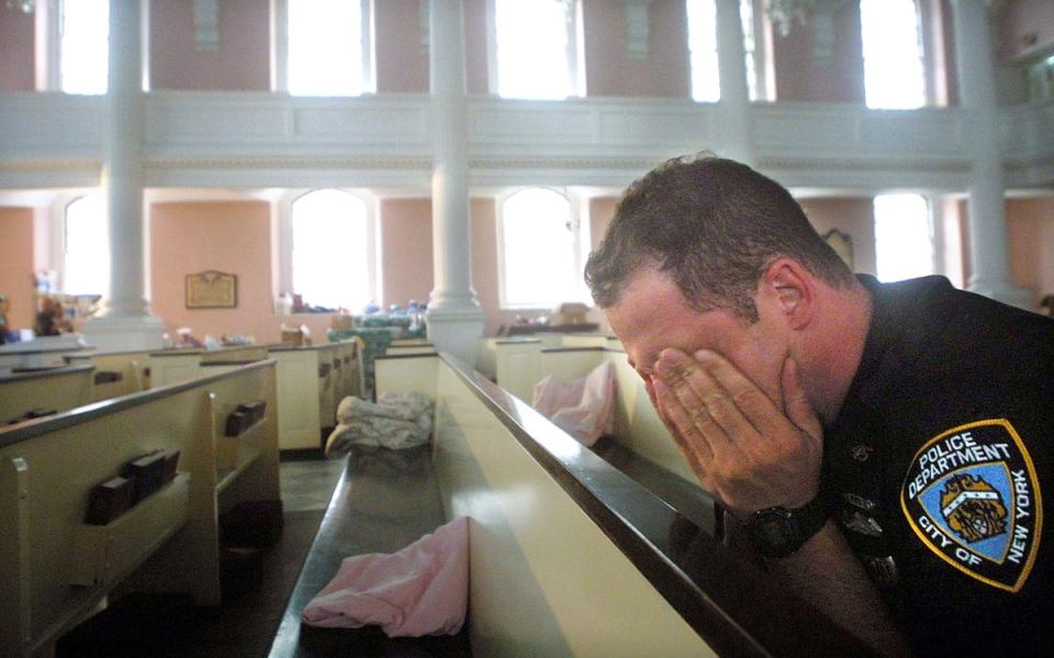 NYPD police officer Ken Radigan rubs his eyes after briefly sleeping in a pew at St Paul’s Episcopal Chapel, near the site of the World Trade Center attack. The chapel served as a relief area for rescue workers (Getty)