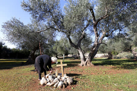 Ermioni Brigo, 85, lights a candle near a Greek World War Two soldier's makeshift grave in Himara, Albania January 26, 2018. Picture taken January 26, 2018. REUTERS/Florion Goga