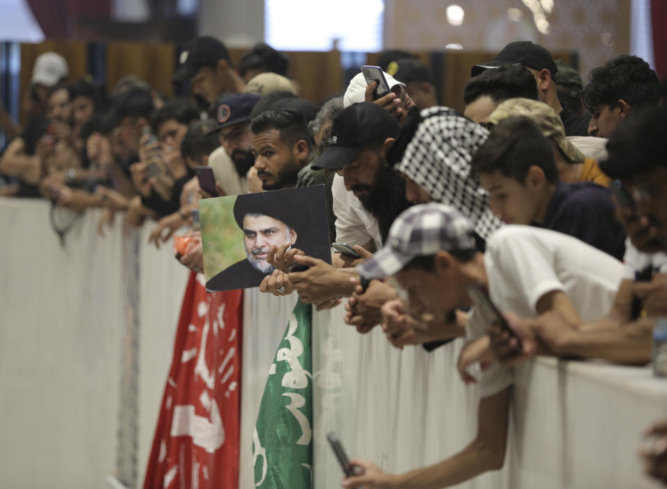 Followers of Shiite cleric Muqtada al-Sadr hold posters with his photo during a sit-in, inside the parliament in Baghdad, Iraq, Monday, Aug. 1, 2022. The political rivals of al-Sadr whose followers stormed the parliament have declared their own counter-protest. The announcement on Monday stirred fear among Iraqis and caused security forces to erect concrete barriers leading to the heavily fortified Green Zone, home of the parliament building. (AP Photo/Anmar Khalil)