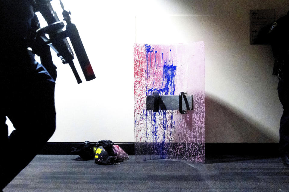 A paint-splattered riot shield sits in a hallway at the Mark O. Hatfield U.S. Courthouse as federal officers faced off with protesters Saturday, July 25, 2020, in Portland, Ore. On the streets of Portland, a strange armed conflict unfolds night after night. It is raw, frightening and painful on both sides of an iron fence separating the protesters on the outside and federal agents guarding a courthouse inside. This weekend, journalists for The Associated Press spent the weekend both outside, with the protesters, and inside the courthouse, with the federal agents, documenting the fight that has become an unlikely centerpiece of the protest movement gripping America. (AP Photo/Noah Berger)