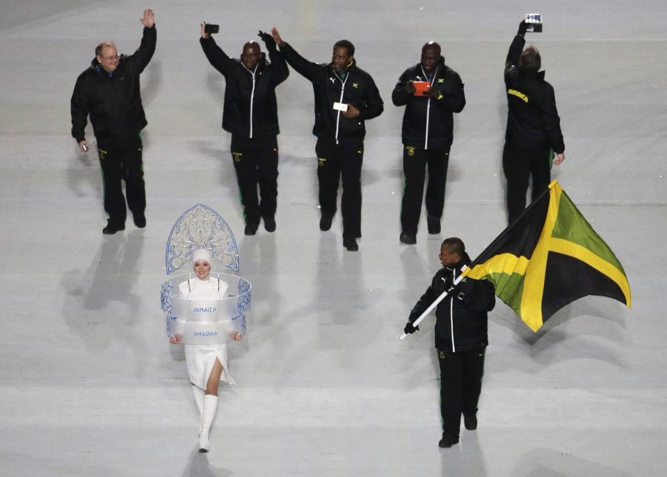 Marvin Dixon of Jamaica holds his national flag and enters the arena with teammates during the opening ceremony of the 2014 Winter Olympics in Sochi, Russia, Friday, Feb. 7, 2014. (AP Photo/Charlie Riedel)