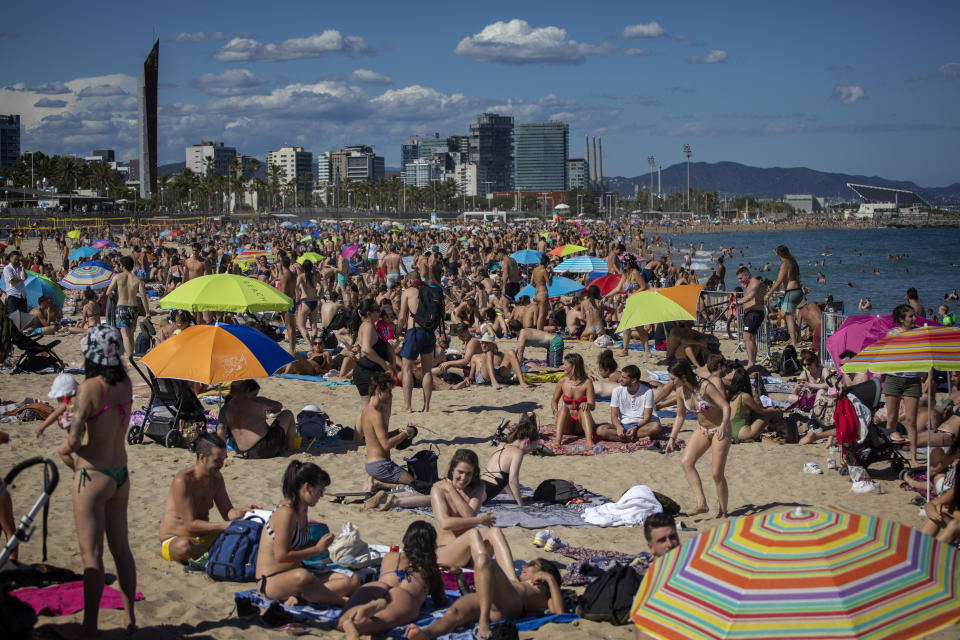 FILE - In this Saturday, June 13, 2020 file photo, people enjoy the warm weather on the beach in Barcelona, Spain. European Union envoys are close to finalizing a list of countries whose citizens will be allowed back into Europe once it begins lifting coronavirus-linked restrictions. The United States appears almost certain not to make the list, as new infections surge and given that President Donald Trump has imposed a ban on European travelers. (AP Photo/Emilio Morenatti, File)