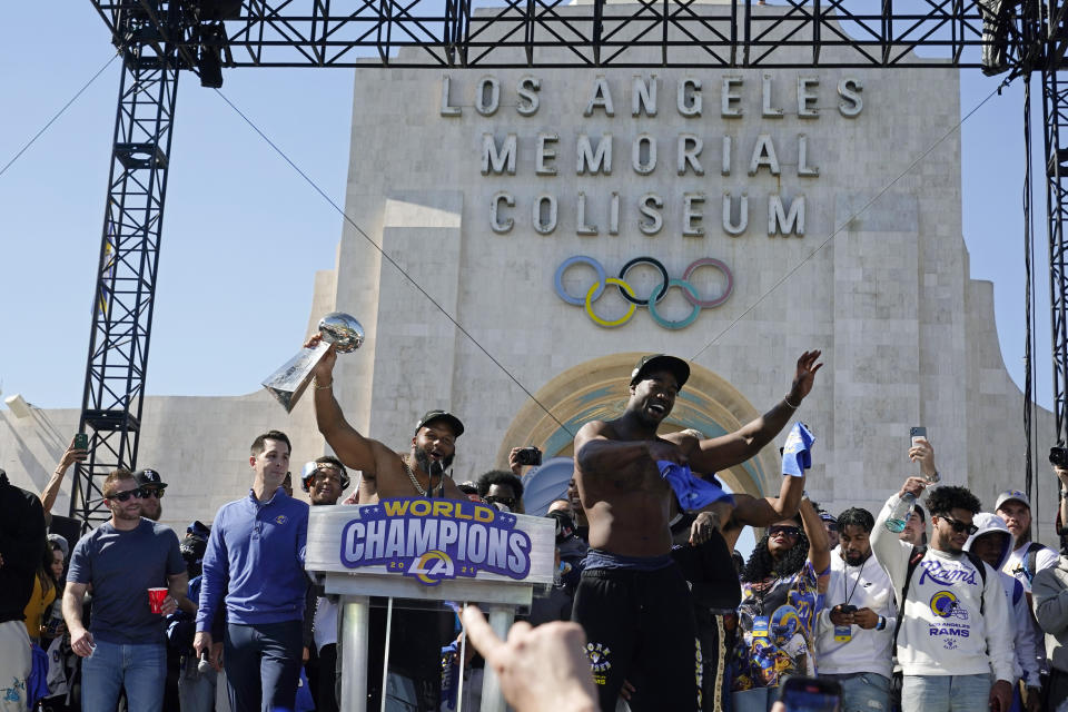 Los Angeles Rams defensive lineman Aaron Donald, center, holds up the Vince Lombardi Super Bowl trophy as he celebrates with linebacker Ogbonnia Okoronkwo, right, during the team's victory celebration at Los Angeles Memorial Coliseum in Los Angeles, Wednesday, Feb. 16, 2022. The Rams beat the Cincinnati Bengals Sunday in the NFL Super Bowl 56 football game. (AP Photo/Marcio Jose Sanchez)