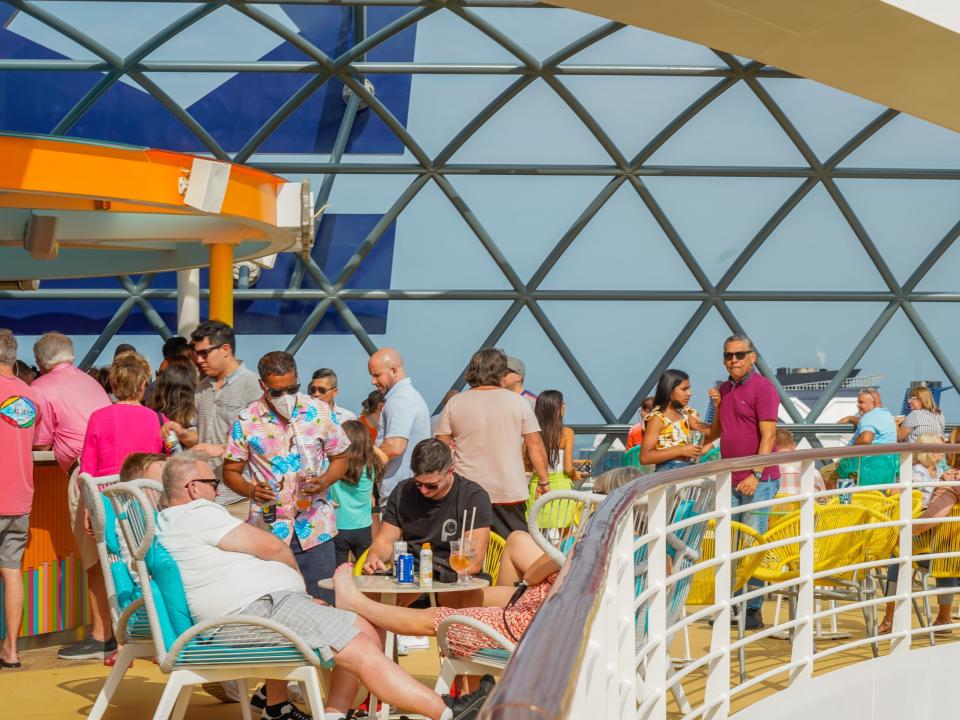 People on the top deck of Wonder of the Seas enjoy drinks at the bar