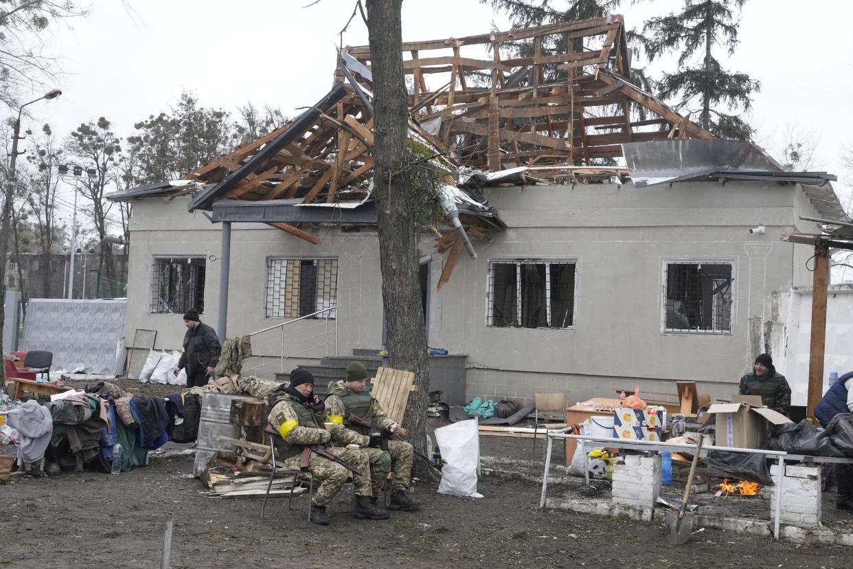 Ukrainian servicemen sit in front of a damaged house near a checkpoint in Brovary, outside Kyiv, Ukraine, Tuesday, March 1, 2022.