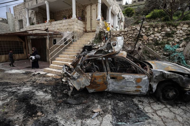 People look at a damaged car after an Israeli army operation in the Jenin camp in the West Bank. Three people have been killed, the Israeli army reported. Ayman Nobani/dpa