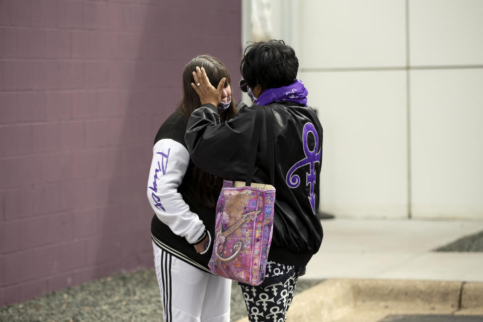 Patrice Files of Detroit, Mich. wipes the tears off the face of friend Virginia Ann Rausch of Blaine, Minn., Wednesday, April 21, 2021, outside of Paisley Park in Chanhassen, Minn., on the fifth anniversary of Prince's death. Fans were allowed into the home and studio of the late musician 20 at a time to pay respect. Files said she "felt the need to be here, not only as a fan but also as a family member, because that is what his fans were to him - family." (AP Photo/Stacy Bengs)