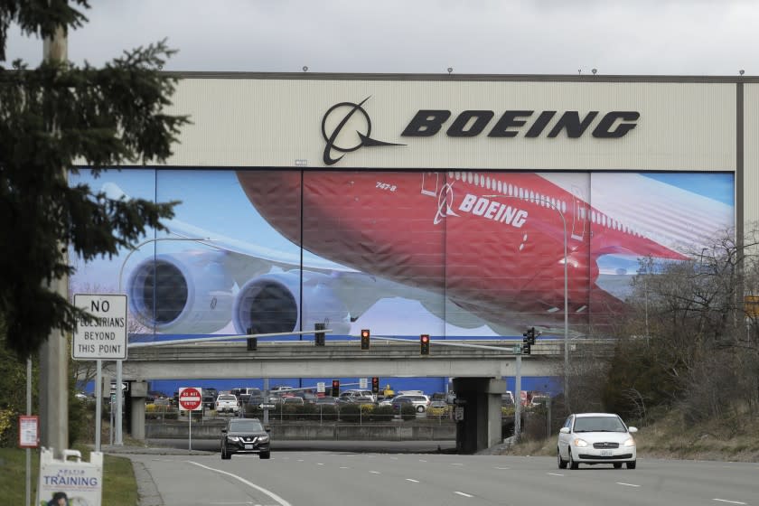 FILE - In this March 23, 2020, file photo, cars are driven near Boeing's manufacturing facility in Everett, Wash., north of Seattle. Boeing says it will resume production of its commercial airplanes in phases at its Seattle area facilities next week after suspending operations in March because of the COVID-19 pandemic. The company says 27,000 of its employees will return to work under new measures put in place to keep people safe and fight the spread of the virus. Employees for the 737, 747, 767 and 777 airplanes will return as early as Monday, April 20, with most returning to work by Tuesday, officials said. (AP Photo/Ted S. Warren, File)