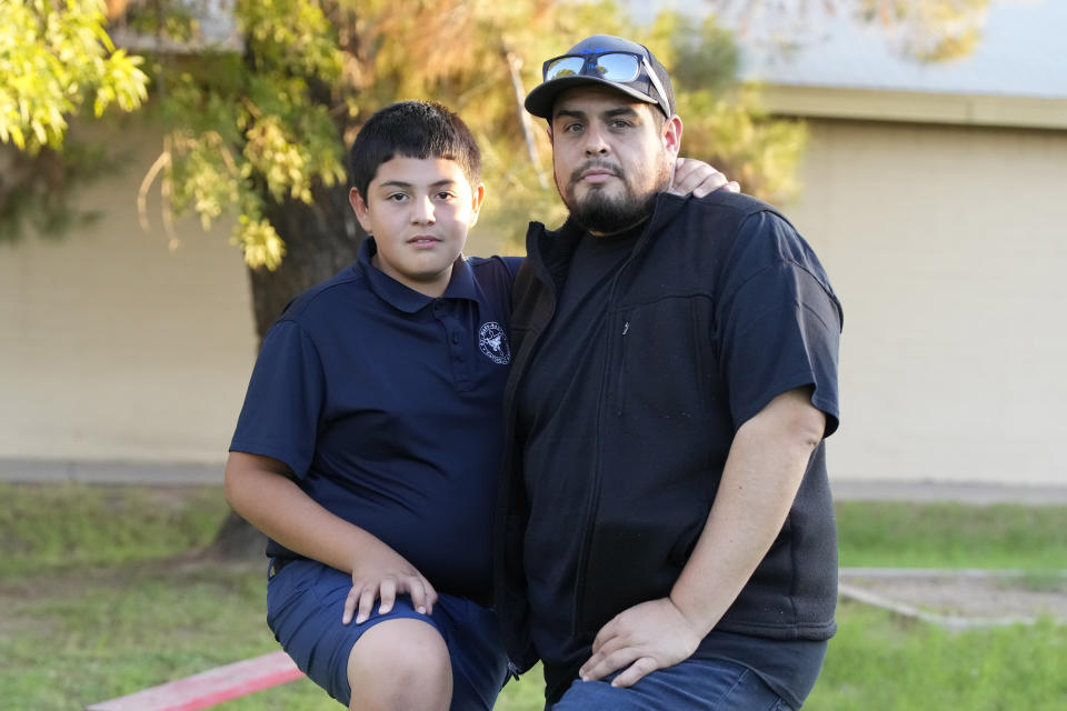 Aaron Galaz and his son pose for an image on Wednesday, Oct. 18, 2023 in Phoenix. Aaron Galaz said his son is enrolled in a program that uses taxpayer funds to pay for private-school tuition in part so his son could be challenged more in class. At least four states that have made most children eligible for taxpayer-funded scholarships to private schools are seeing more families using the programs than planned. That could cost taxpayers, but it's early to know the exact budget implications. (AP Photo/Rick Scuteri)