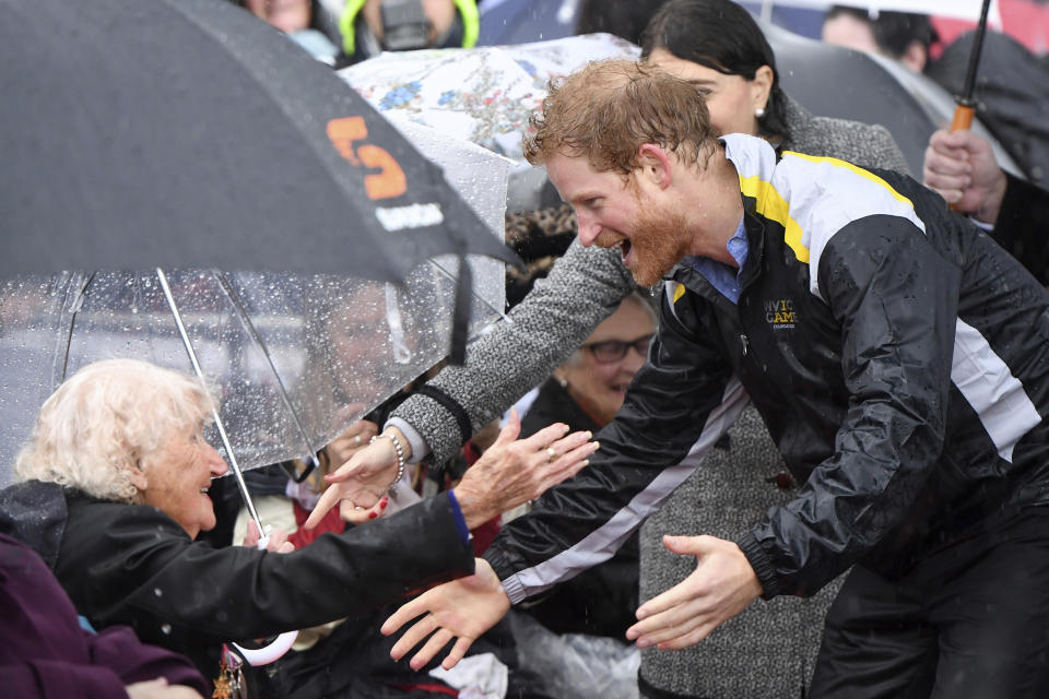 FILE - In this June 7, 2017, file photo, Britain's Prince Harry, right, meets Daphne Dunne, 97, left, during a rainy walk in Sydney. There seems to be a special bond between Harry and Dunne, a war widow who gave him a warm hug Tuesday, Oct. 16, 2018, when they met in Sydney. It’s become a regular thing for the two of them. Dunne, tries to come cross the prince’s path whenever he comes to Australia. (Dean Lewins/Pool Photo via AP, File)