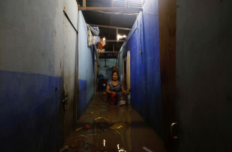 A woman salvages her belongings from her house in an area that was flooded by the overflowing of the Bagmati river following heavy rains, in Kathmandu