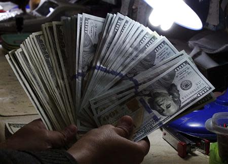 A money changer inspects U.S. dollar bills at a currency exchange in Manila January 15, 2014. REUTERS/Romeo Ranoco