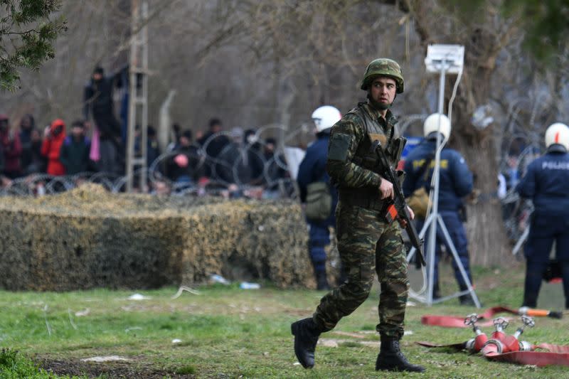 A Greek soldier patrols as migrants who want to cross into Greece from Turkey are gathered at the borderline, at the closed Kastanies border crossing with Turkey's Pazarkule, in the region of Evros