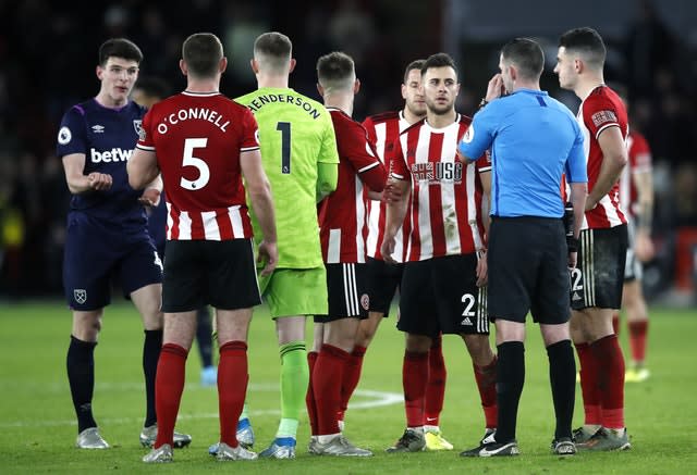 Players wait with referee Michael Oliver for the VAR decision