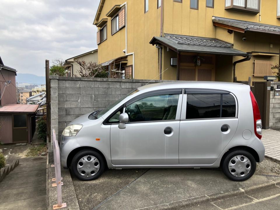A Honda Life kei car parked in a small driveway in Japan
