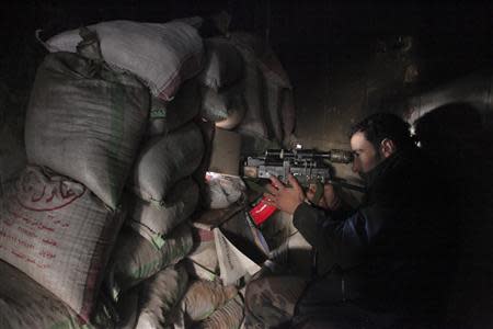 A Syrian army soldier loyal to Syria's President Bashar al-Assad points his weapon through piled sandbags at the Justice Palace in the old city of Aleppo, February 10, 2014. REUTERS/George Ourfalian