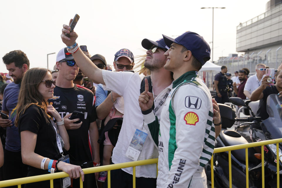 Alex Palou, right, takes a photo with a fan after winning the IndyCar Detroit Grand Prix auto race, Sunday, June 4, 2023, in Detroit. (AP Photo/Carlos Osorio)