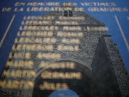 Los restos de la antigua iglesia se reflejan en el monumento de guerra de los pueblos en Graignes, Francia, el 15 de mayo de 2019. REUTERS/Christian Hartmann/Files