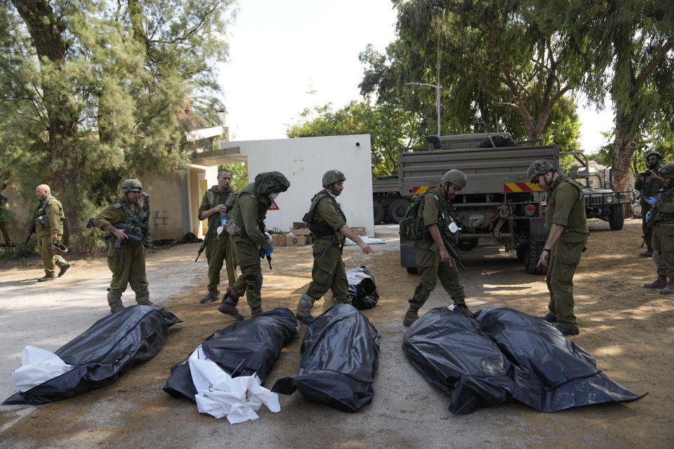 Israeli soldiers stand next to the bodies of Israelis killed by Hamas militants in kibbutz Kfar Azza on Tuesday, Oct. 10, 2023. Hamas militants overran Kfar Azza on Saturday, where many Israelis were killed and taken captive. (AP Photo/Ohad Zwigenberg)