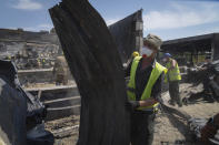 Workers clear away debris at a shopping center burned down in a Russian rocket attack in Kremenchuk, Ukraine, Wednesday, June 29, 2022. (AP Photo/Efrem Lukatsky)