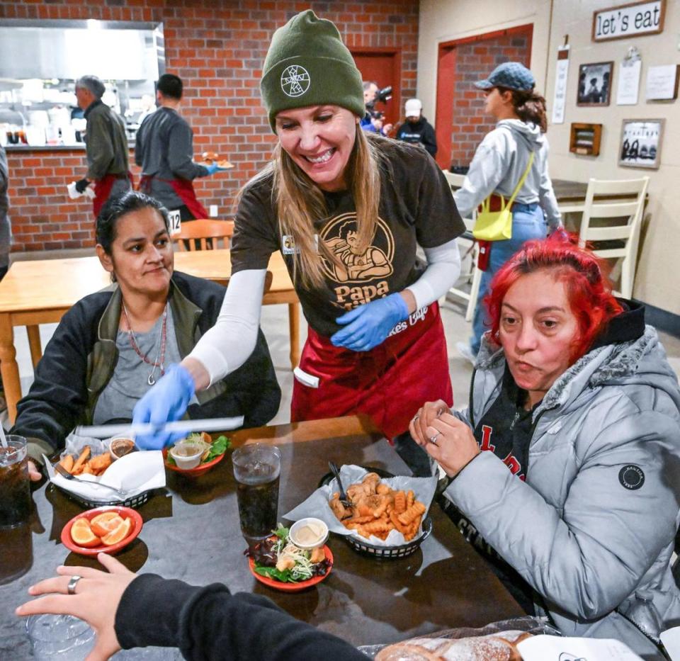 Volunteer and Poverello House board member Heidi Michael serves guests at the new Papa Mike’s Café, a restaurant-style cafe serving no-cost meals to anyone who wants one, during its grand opening at the Poverello House on Wednesday, Jan. 24, 2024.