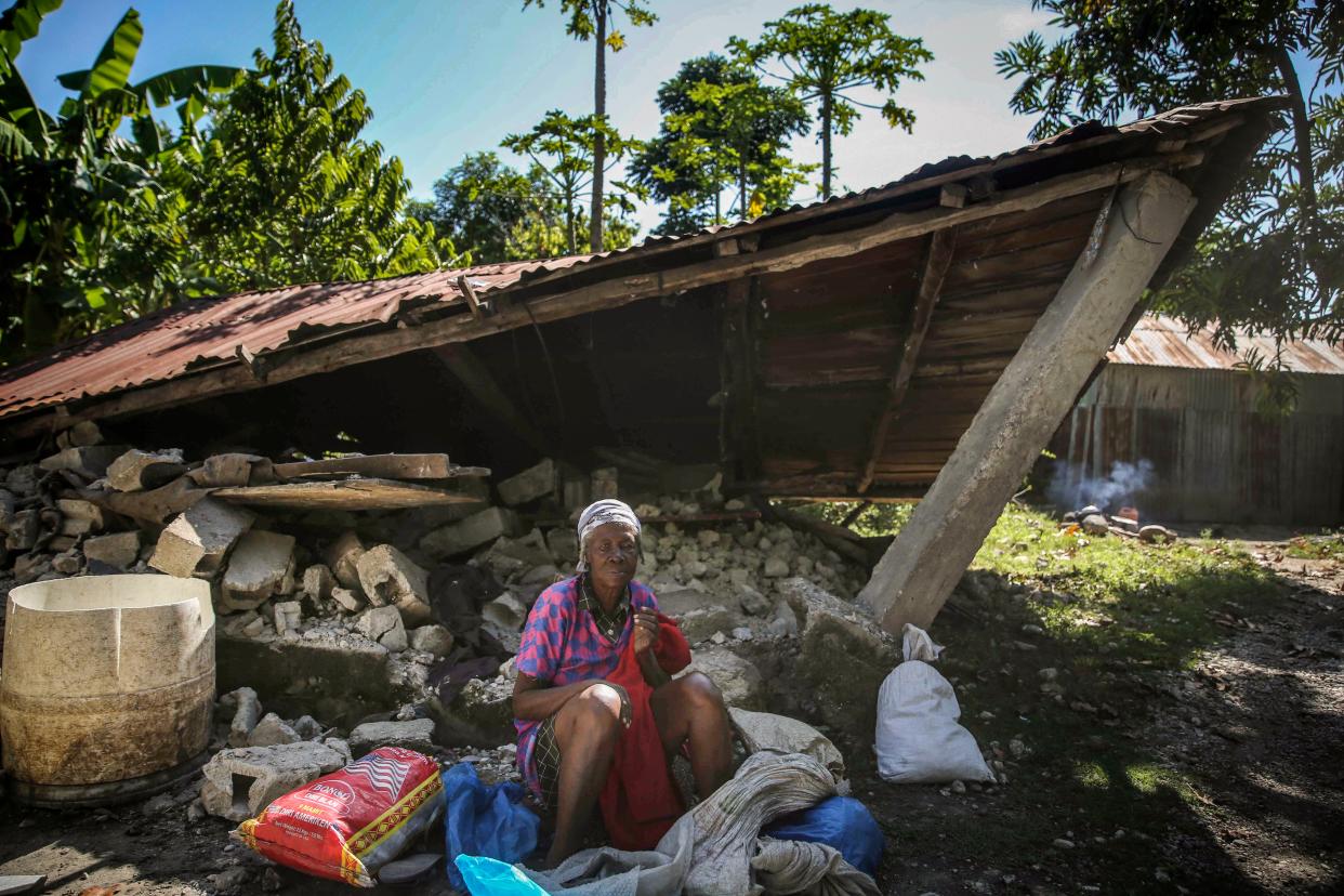 A woman sits in front of a destroyed house after the earthquake in Camp-Perrin, Les Cayes, Haiti, Sunday, Aug. 15, 2021.