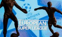Metal figures of football players are seen in front of the words "European Super League" and the UEFA Champions League logo in this illustration